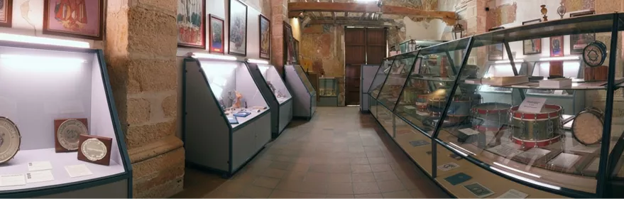 Pasillo de museo con vitrinas y tambores expuestos en una larga vitrina lateral.