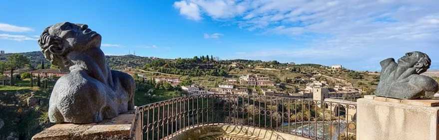 Mirador con bustos escultóricos y vistas al valle bajo cielo azul.
