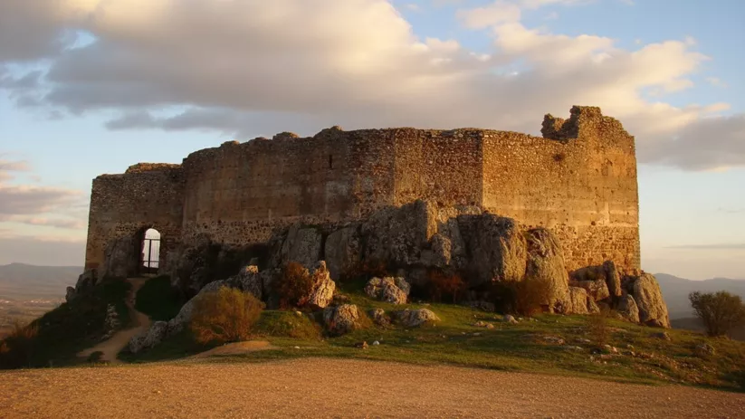 Castillo de Milagro en Navalpino (Ciudad Real), fortaleza medieval sobre formaciones rocosas al atardecer.