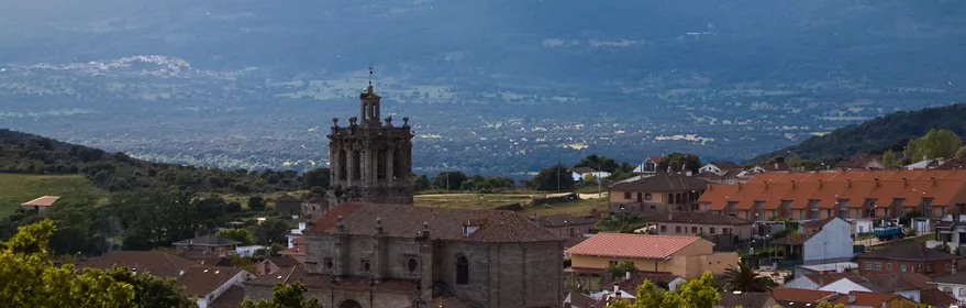 Iglesia de piedra entre tejados con montañas al fondo