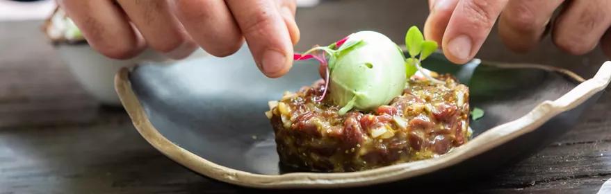 Manos decorando tartar con crema verde