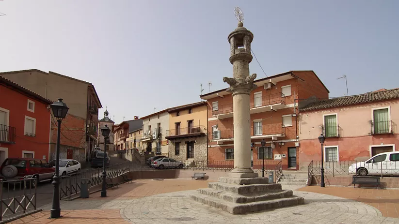 Plaza con columna de piedra y casas alrededor