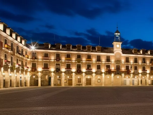 Plaza monumental iluminada de noche con arcos y reloj