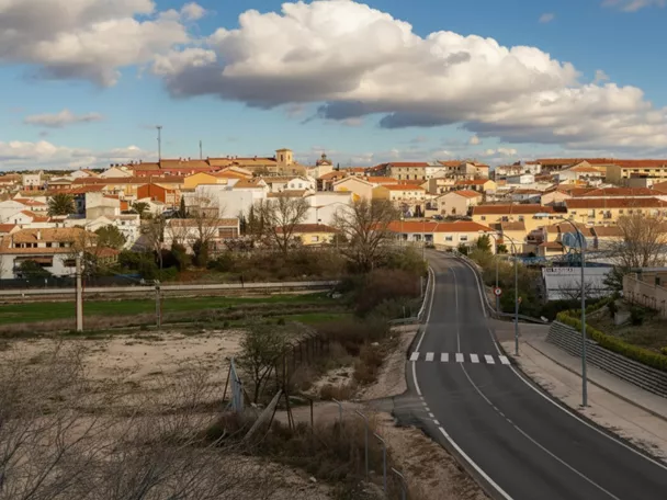 Carretera de entrada al pueblo con casas y cielo nuboso
