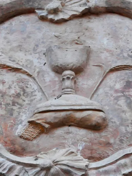 Detalle de relieve escultórico en piedra con forma ornamental en una fachada.