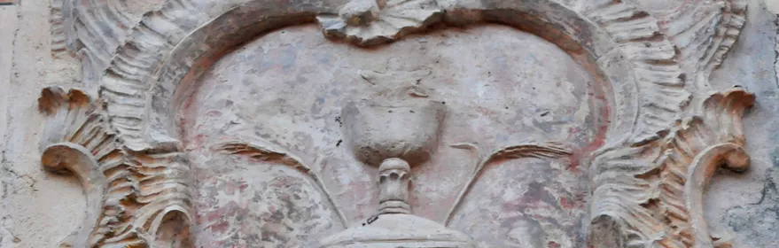 Detalle de relieve escultórico en piedra con forma ornamental en una fachada.