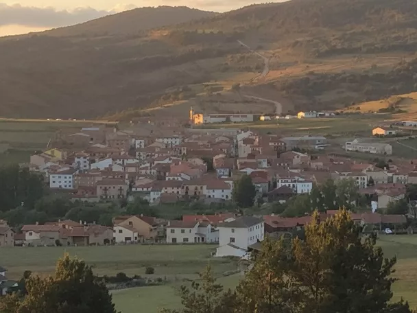 Vista panorámica de pueblo de montaña rodeado de prados y colinas.