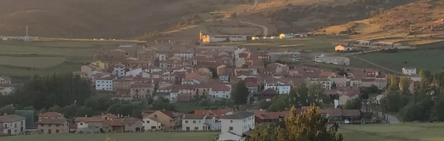 Vista panorámica de pueblo de montaña rodeado de prados y colinas.
