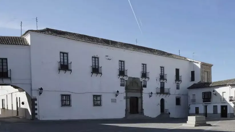 Fachada blanca de edificio histórico en una plaza soleada