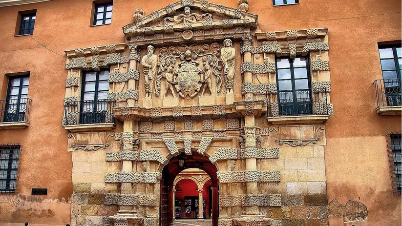 Fachada histórica con portada tallada en piedra y balcones simétricos.