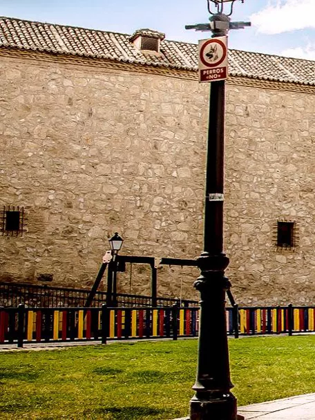Plaza con jardines frente a una gran fachada de piedra