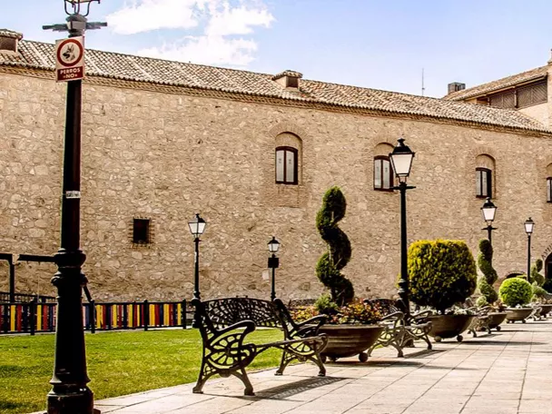 Plaza con jardines frente a una gran fachada de piedra