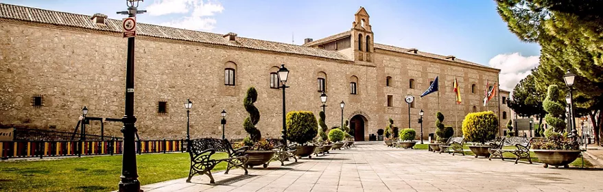 Plaza con jardines frente a una gran fachada de piedra