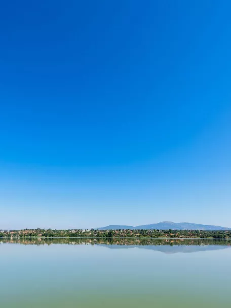 Vista panorámica de un lago en calma con reflejos y cielo azul
