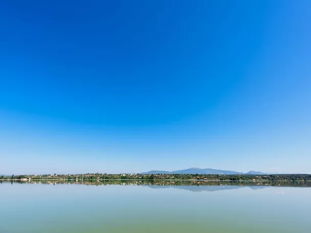 Vista panorámica de un lago en calma con reflejos y cielo azul