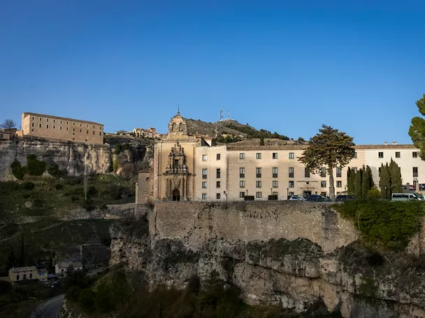 Edificio monumental sobre muralla con colina al fondo.