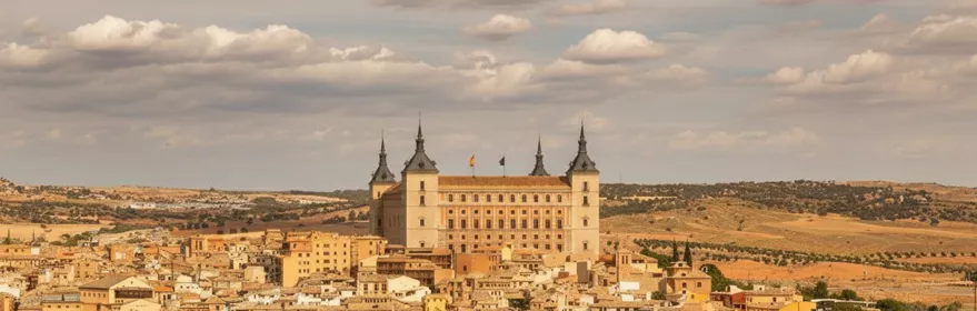 Terraza con copas frente a panorámica urbana dominada por gran edificio monumental.