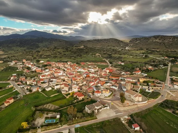 Vista aérea de un pueblo entre montes con rayos de sol