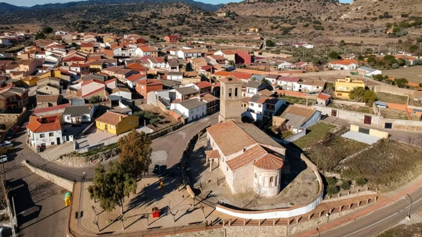 Vista aérea de un pueblo con iglesia y colinas alrededor