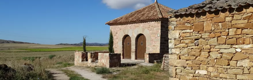 Núcleo rural entre colinas y prados al atardecer.