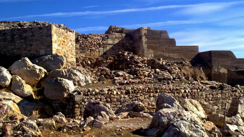 Restos de murallas de piedra entre rocas bajo cielo azul