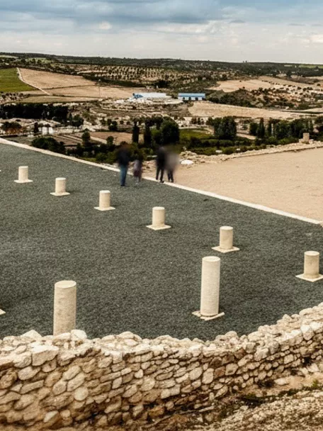 Ruinas arqueológicas con columnas bajas y muros de piedra en una colina.
