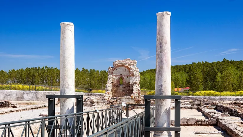 Restos arqueológicos con columnas de piedra y pasarela metálica
