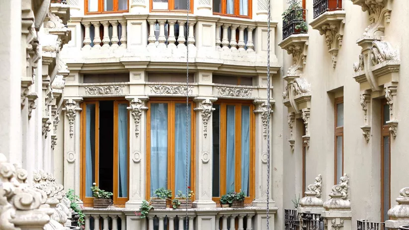 Ventanas y balcones ornamentados en un patio interior con detalles clásicos en piedra.