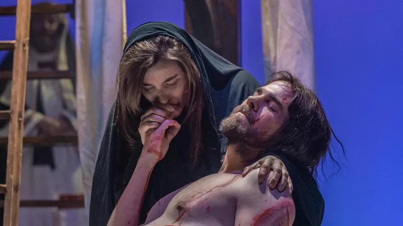 Mujer arropa a un hombre herido en una escena teatral