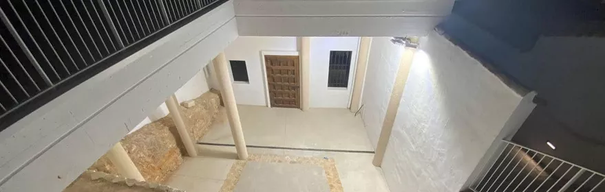 Patio interior excavado con muros blancos y pasarelas superiores