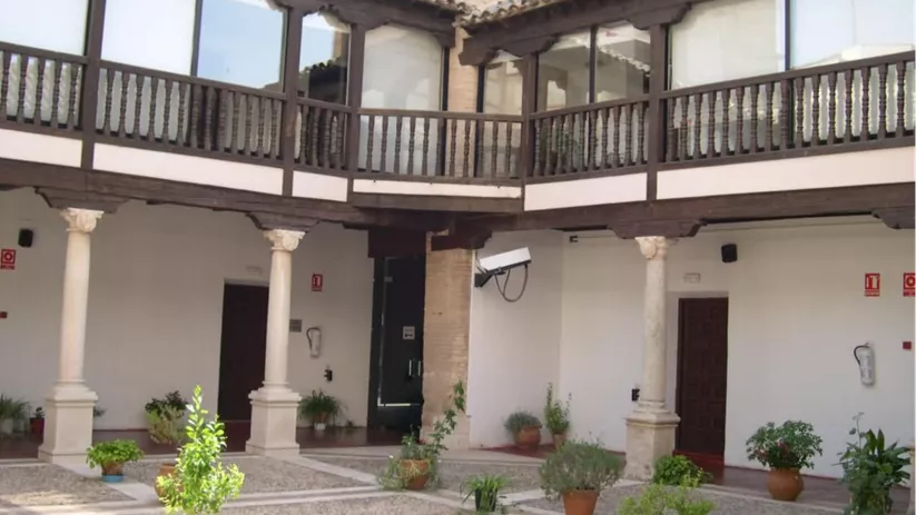 Patio interior con columnas, balconada de madera y macetas