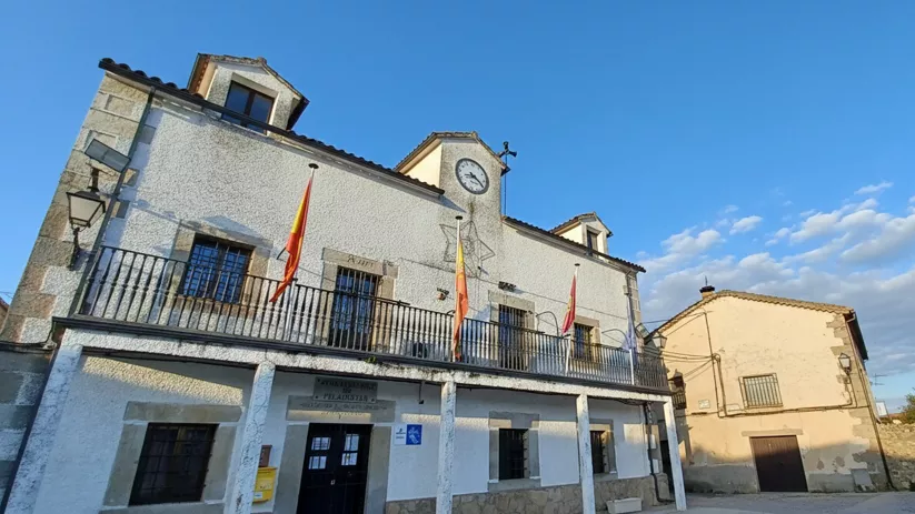 Ayuntamiento blanco con reloj y banderas