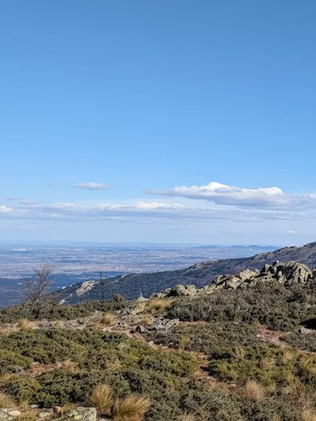 Cresta montañosa con formaciones rocosas y camino visible entre colinas.