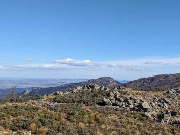 Cresta montañosa con formaciones rocosas y camino visible entre colinas.