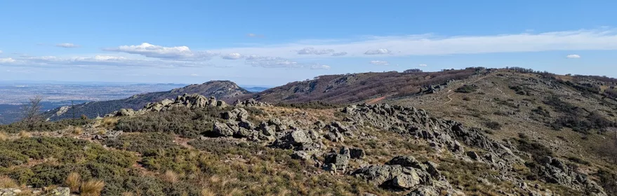 Cresta montañosa con formaciones rocosas y camino visible entre colinas.