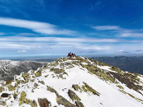 Montañeros en la cumbre de una montaña nevada.