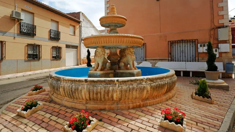 Plaza del pueblo con fuente sostenida por leones