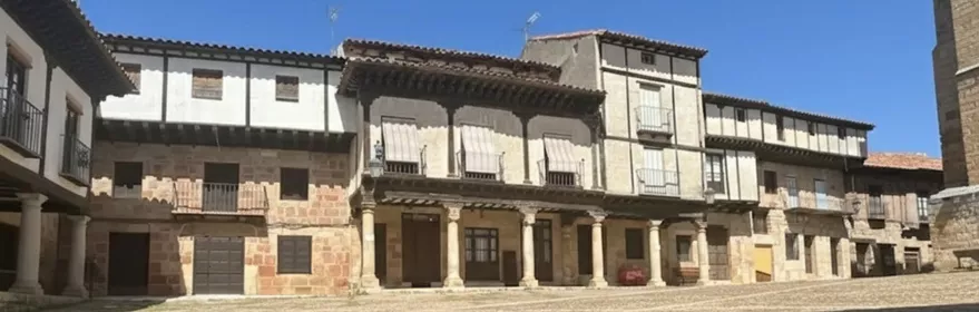 Casas con galerías y soportales alrededor de plaza de suelo empedrado.