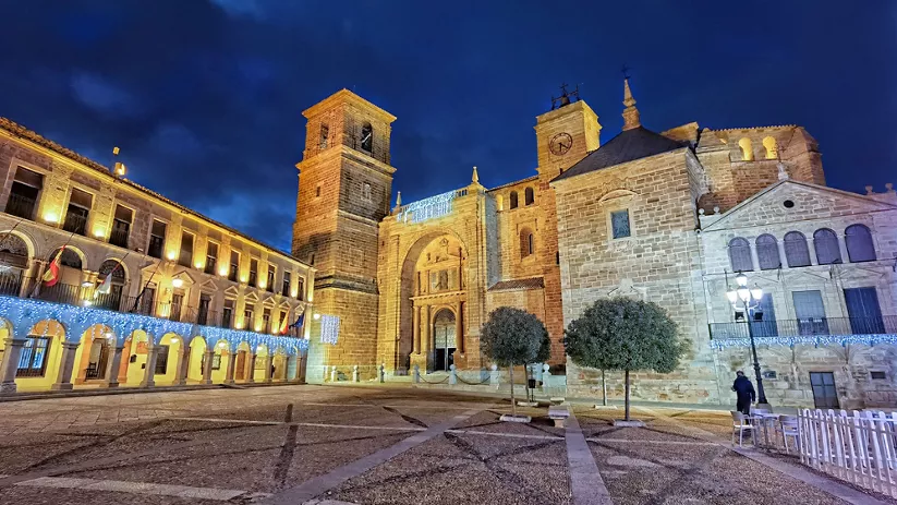 Plaza histórica iluminada con edificio religioso y torre