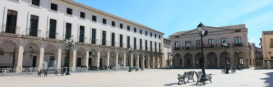  Plaza porticada con bancos y farolas bajo cielo despejado                   