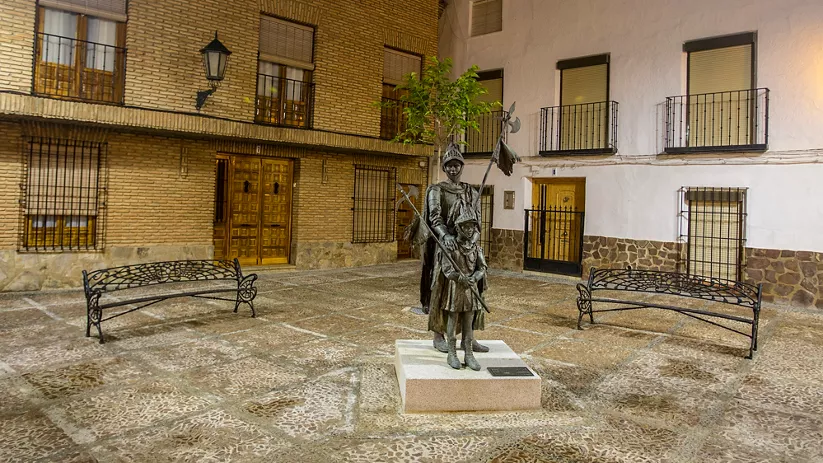 Escultura medieval iluminada en plaza empedrada