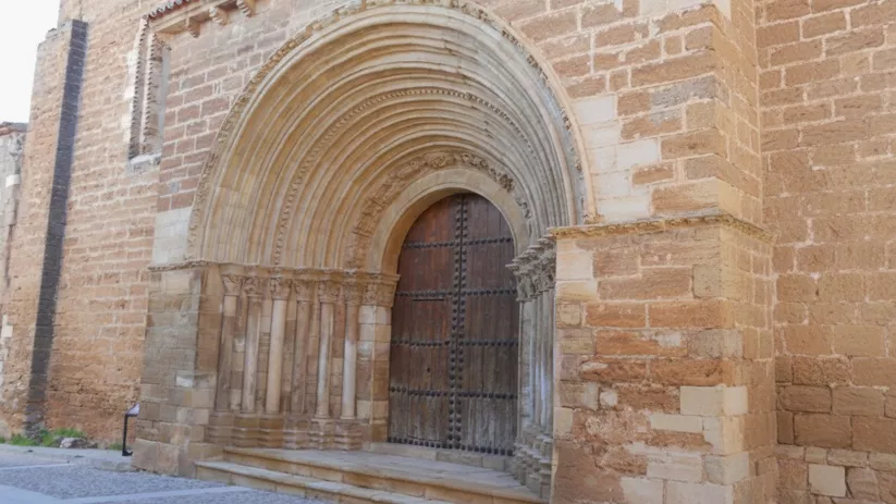 Fachada de iglesia con arco abocinado y capiteles tallados.