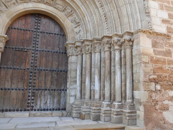 Detalle de portada románica con columnas y puerta de madera.