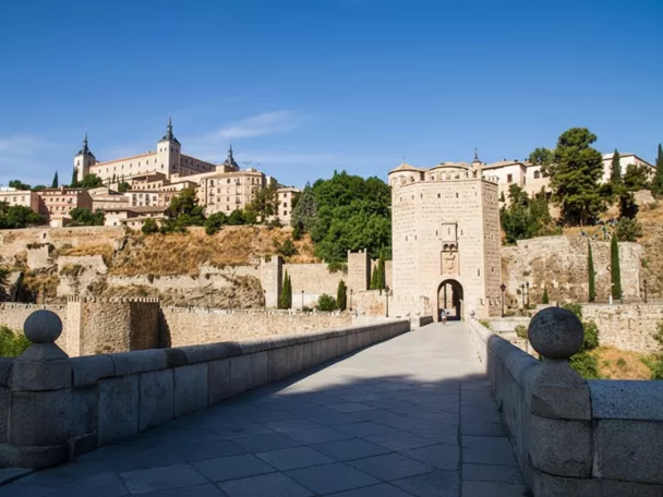 Puente de piedra hacia puerta fortificada y ciudad amurallada