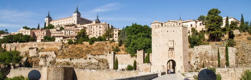 Puente de piedra hacia puerta fortificada y ciudad amurallada