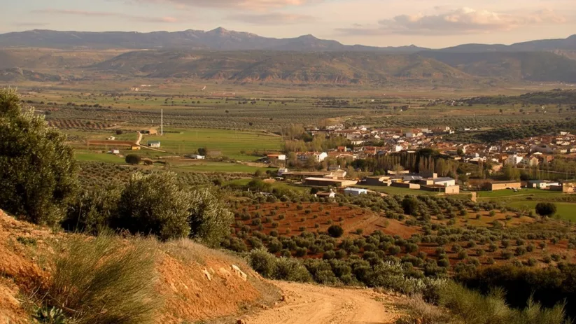 Panorámica de Povedilla rodeado de campos y sierras bajo la luz del atardecer.
