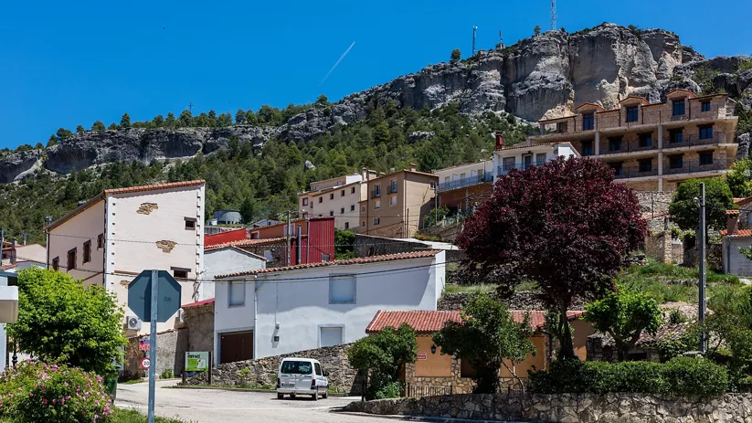 Casas tradicionales al pie de un gran farallón rocoso.