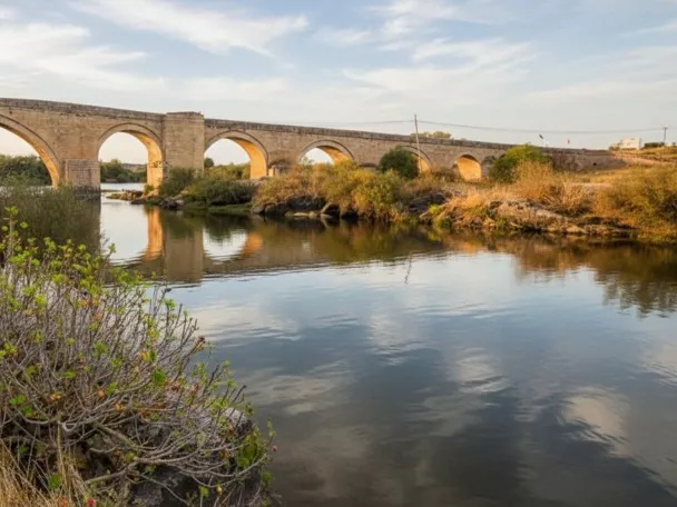 Puente de piedra sobre río con arcos y reflejos