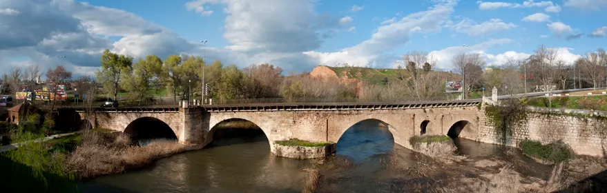 Puente histórico de piedra sobre río.