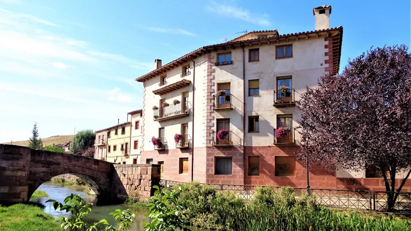 Casas con balcones junto a puente antiguo.